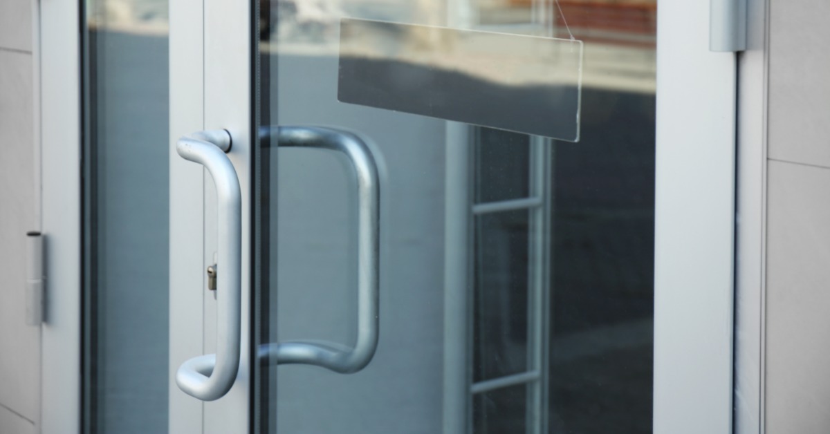 An aluminum door frame with a large handle for people to grab. The door also has a glass pane to see inside.